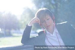 Female in blazer sitting on park bench listening to music on red headphone with sunflare 4Byex5
