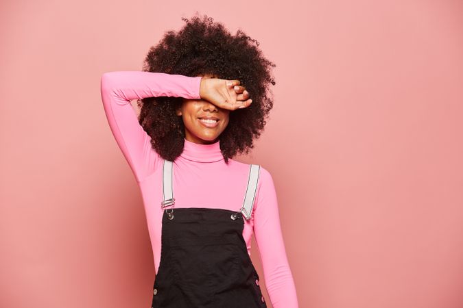 Young Black woman covering eyes with arm
