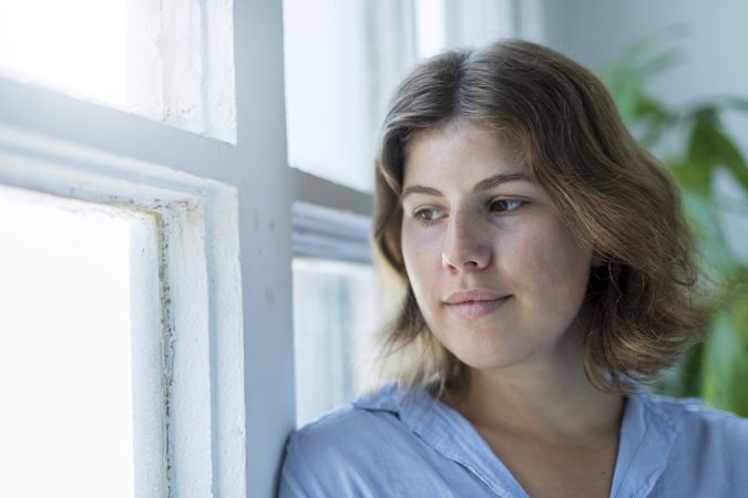 Portrait of serious young woman smiling by window