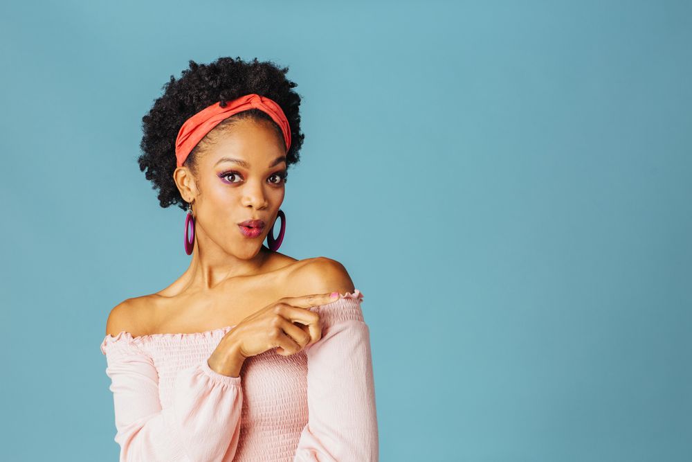 Studio shoot of surprised Black woman pointing her finger to the side