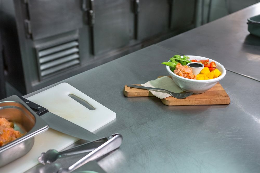 Salmon poke bowl over wooden board ready to eat on restaurant kitchen. Healthy food concept.