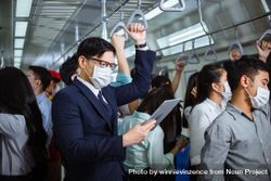 Businessman standing reading tablet in busy metro car 5ll865