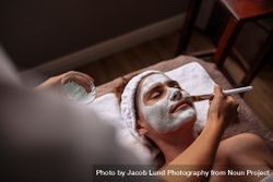 Cosmetician applying facial mask on female face 49mMV6