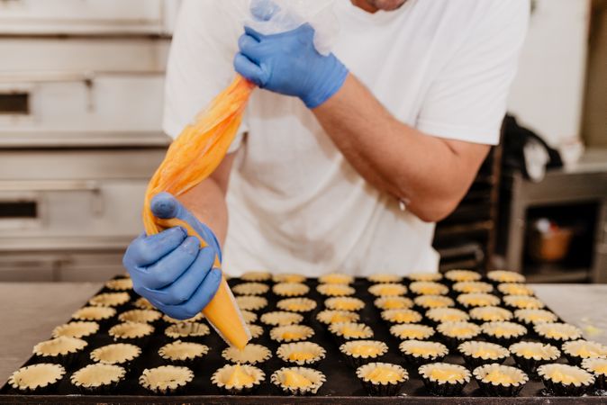 Crop baker filling pastry cases with jelly