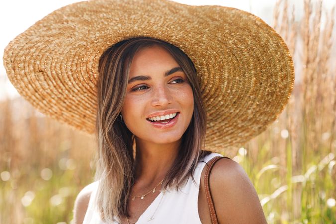 Portrait of content woman in field with straw hat