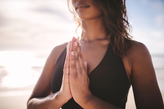 Close-up of fitness woman at beach with her hands joined