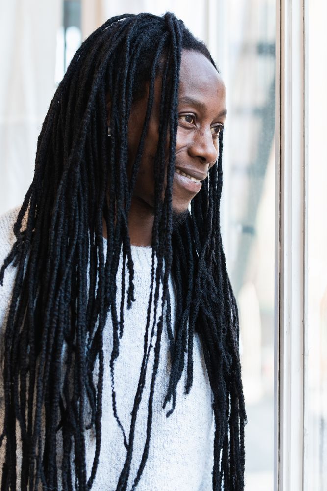 Black man looking at window on street