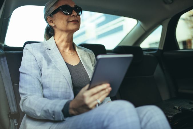 Mature businesswoman in car with tablet pc