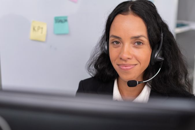 Hispanic employee working at desk to support customers in the office