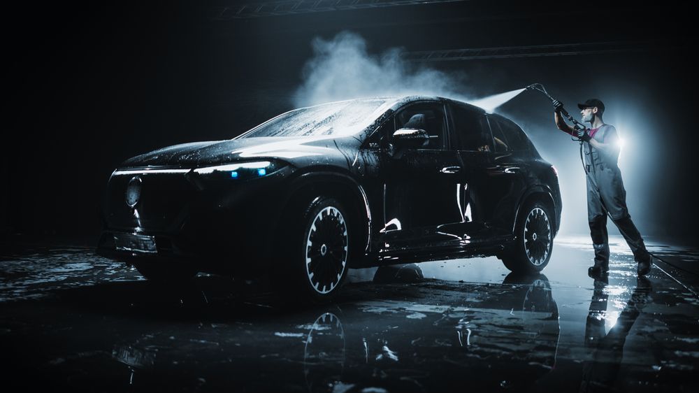 Advertising Style Photo of a Professional Car Wash Specialist Using a High Pressure Washer to Clean and Prepare a High Tech Family Electric SUV