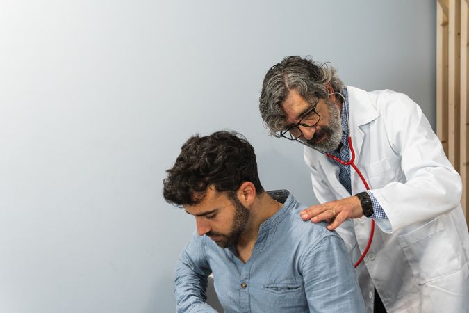 Male doctor using stethoscope and examining patient