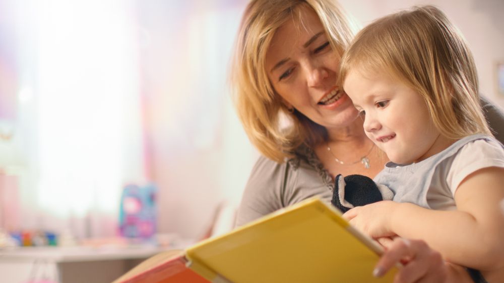 Close-up Shot of a Beautiful Young Mother and Her Little Daughter Read Children's Book Together.