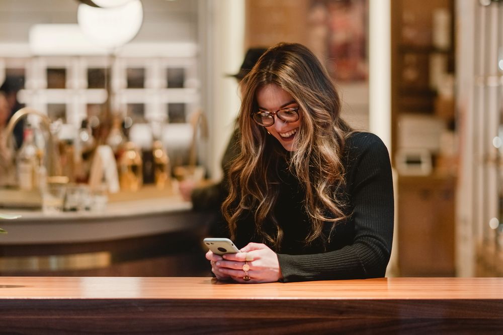 Cheerful female using smartphone in cafe