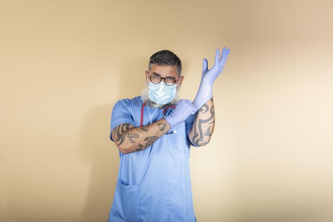 Doctor with facemask wearing elastic gloves