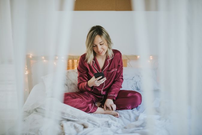 Woman sitting in bed with smartphone