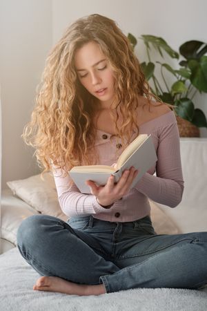 Pensive female in casual clothes reading novel at home