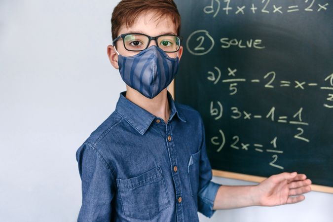 boy with mask in front of a blackboard with equations
