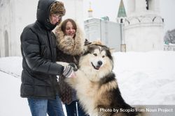 Brother and sister petting Siberian husky on snow covered ground 4NxZr0