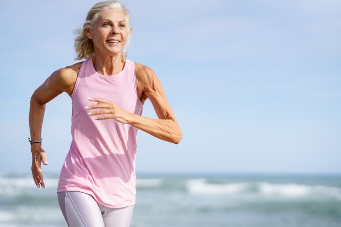 Mature female in athletic gear running along beach