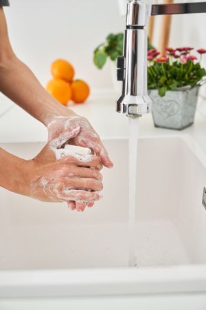 Person washing hands with soap and water in basin