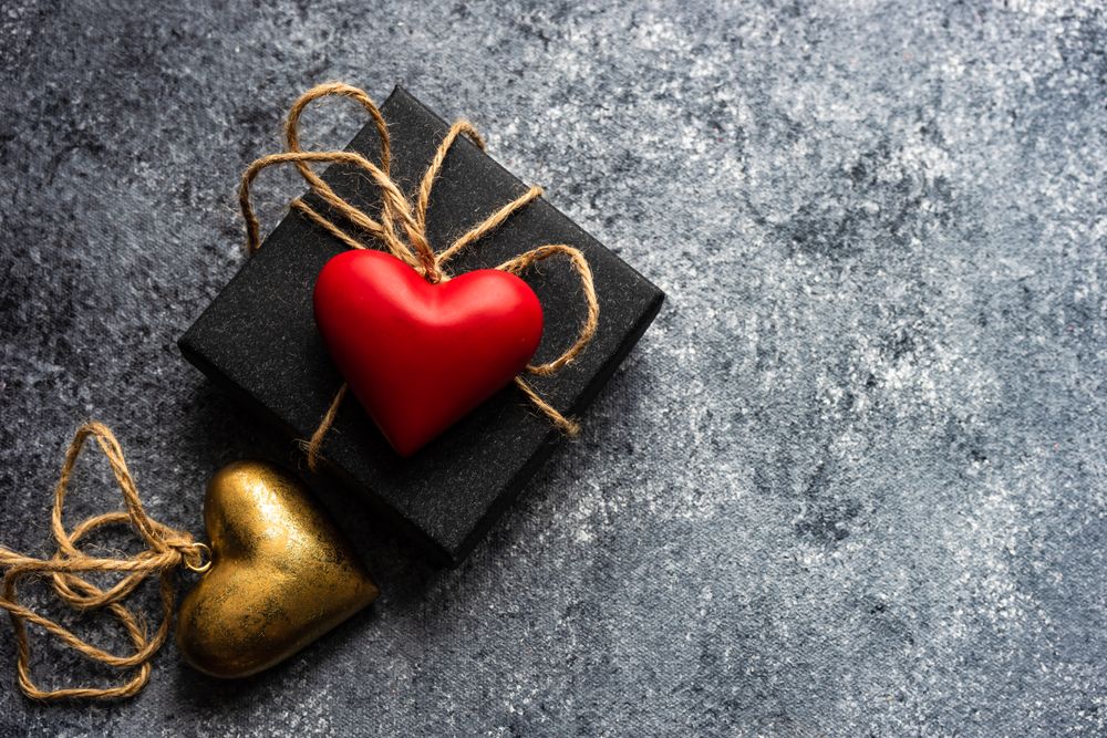 Valentine's day concept with dotted heart shaped decorations on top of present on grey counter