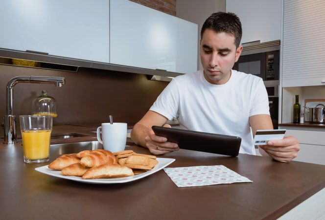 Man sitting at breakfast with credit card and tablet