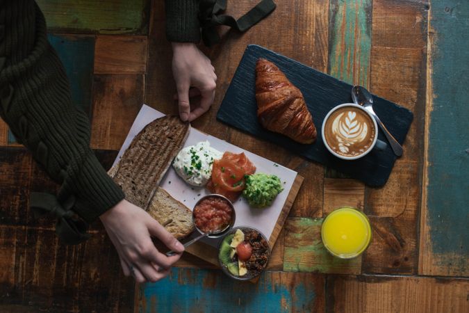 Person reaching for toast on fresh breakfast plate