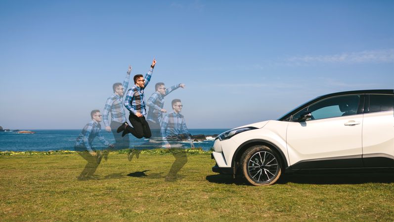 Young man jumping happy with car