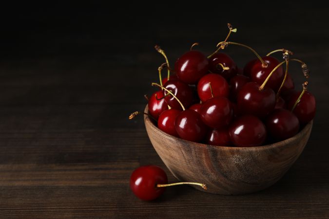 Ripe cherry fruits in a bowl on a wooden background