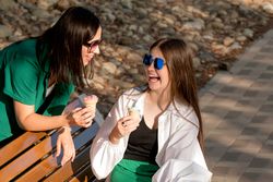Mom and teenage daughter eat ice cream on walk