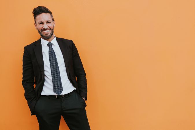 Adult stylish man in costume near orange wall