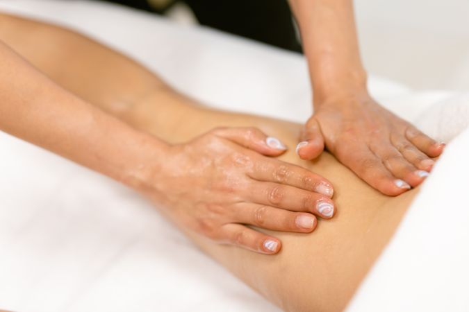 Masseuse giving a deep hamstring massage to a female