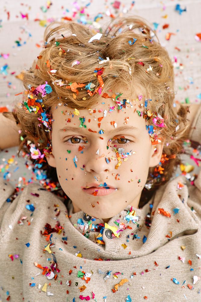 Fair haired kid with confetti on face and clothes