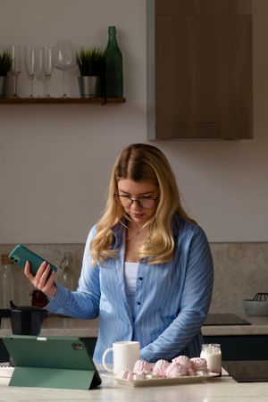 Woman using phone in kitchen with coffee