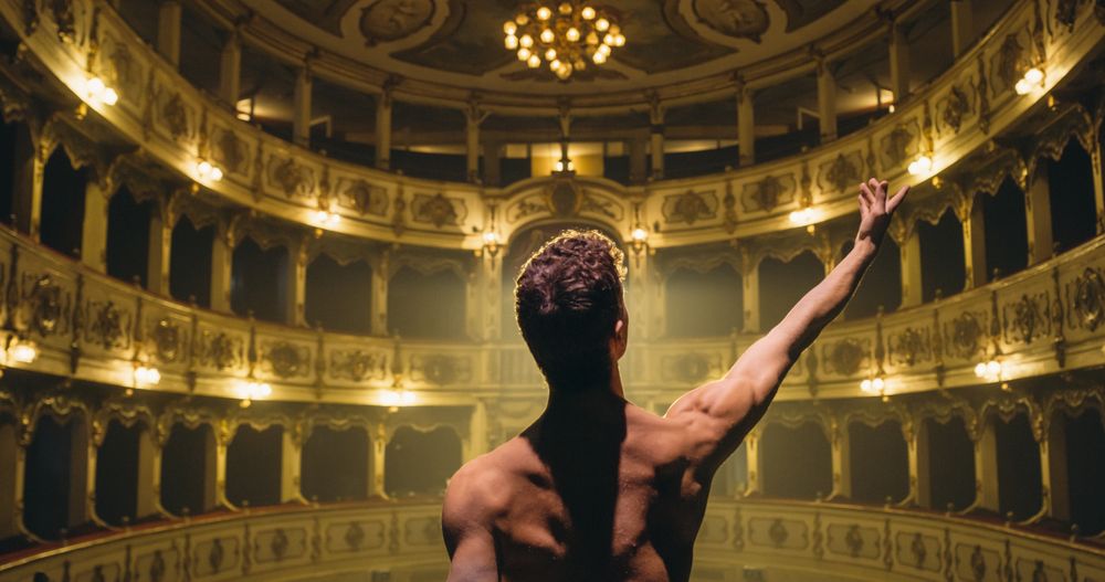 Cinematic Back View of Young Classical Ballet Male Dancer Walking Out to Classic Theatre Stage with Spotlights for the Curtain Call.