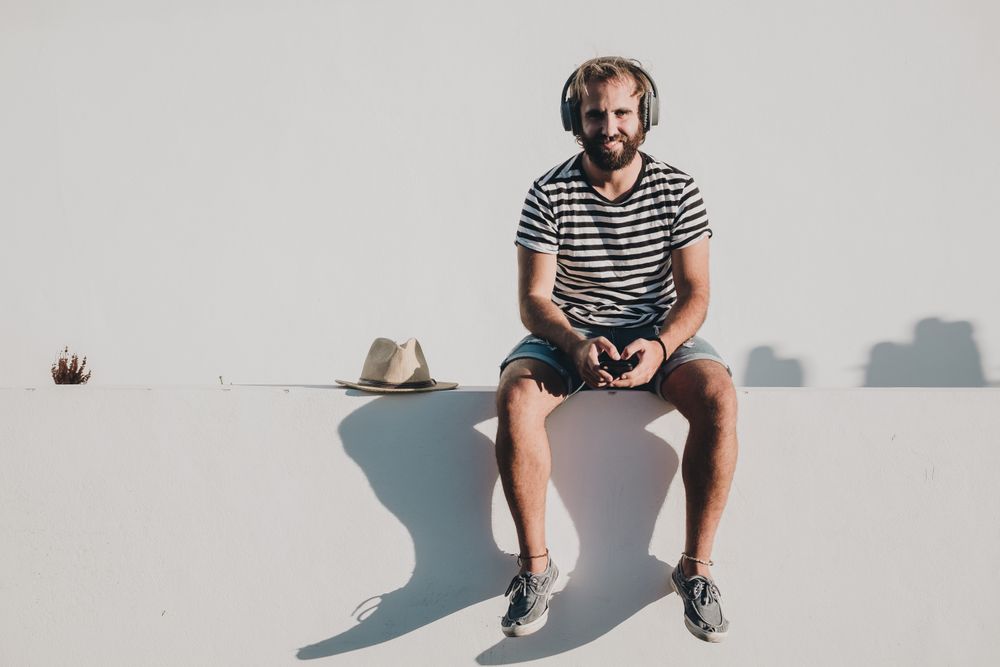 Young male sitting with smartphone and headphones