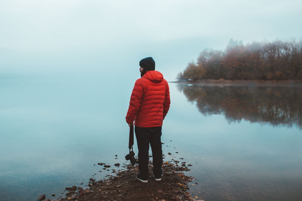 Tourist on empty lake shore in fog