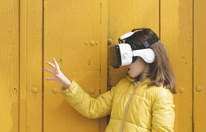 Side view of a girl in yellow jacket wearing VR headset