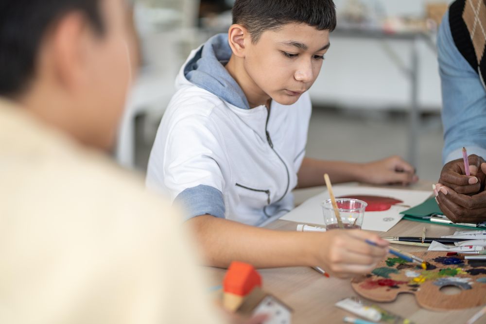 Boy dipping his paint brush in palette