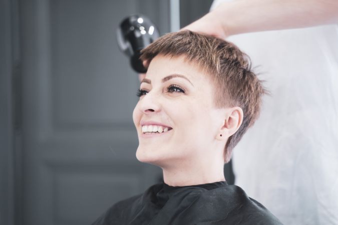 Hairdresser drying hair to woman