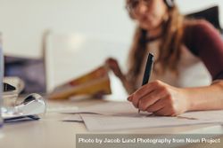 Woman writing notes on paper while working at tech startup 4AdJN5