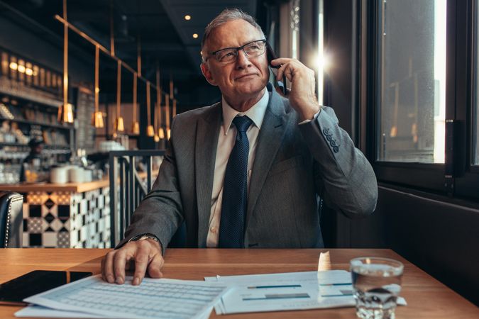 Confident businessman at coffee shop making a phone call
