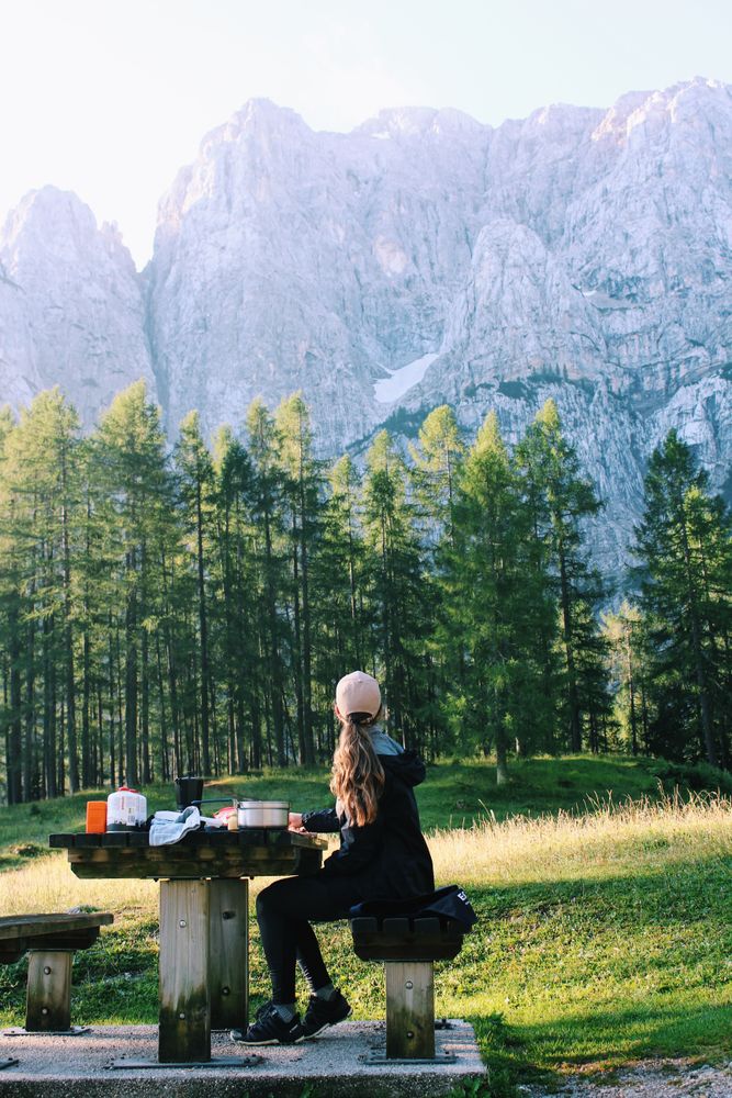 Back view of woman sitting at a concrete table near trees in the woods