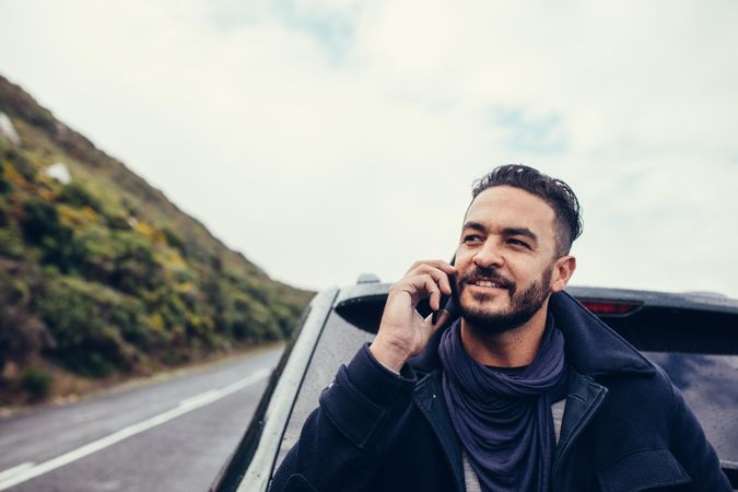 Young man on road trip making a phone call on smartphone