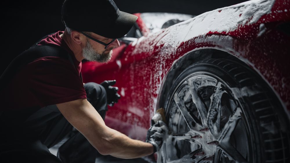 Portrait of an Adult Man Working in a Detailing Studio, Prepping a Factory Fresh American Sportscar for Maintenance Work and Car Care Treatment.