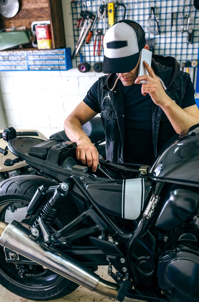 Mechanic talking phone while fixing motorbike