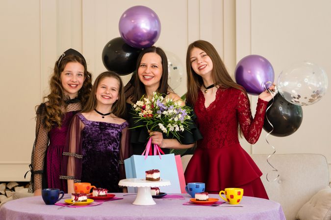 Woman and girls smiling with cake and flowers at birthday