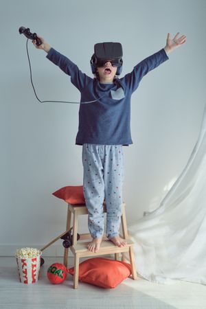 Excited boy playing game in VR goggles