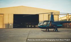 Helicopter is parked outside airplane hangar at airport 56ZMd5