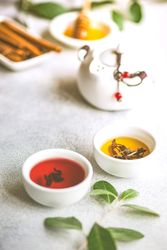 Tea pot on stone background with two colorful cups